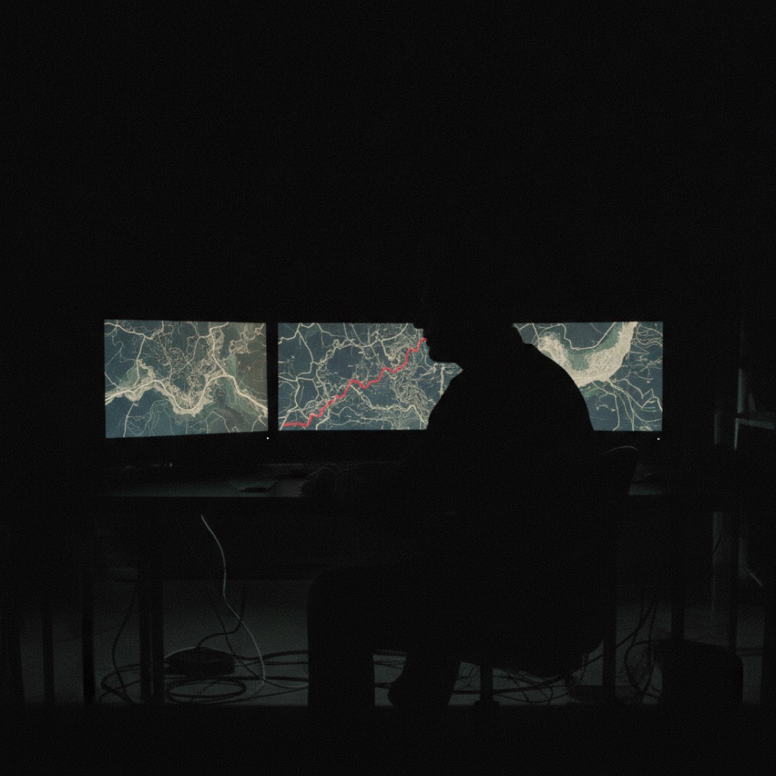 Analyst in silhouette lit by monitors