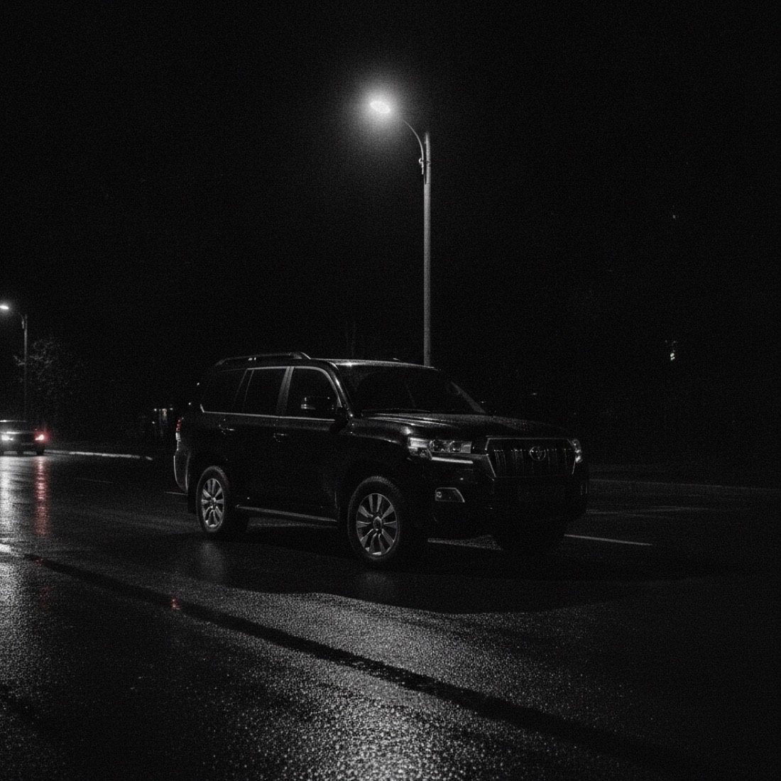 Black Toyota Land Cruiser SUV under a streetlight at night